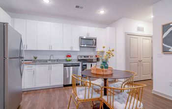 A kitchen with white cabinets and a table and chairs